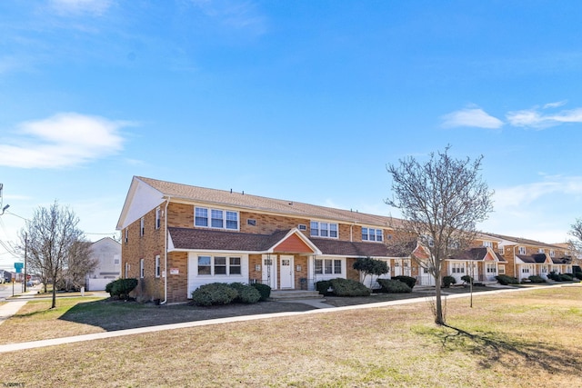 townhome / multi-family property with a front lawn and brick siding