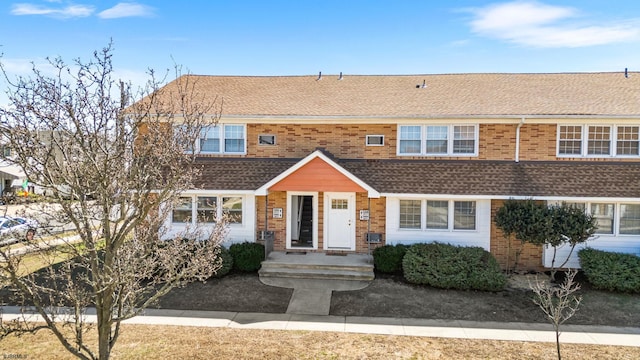 view of front of house with brick siding and a shingled roof