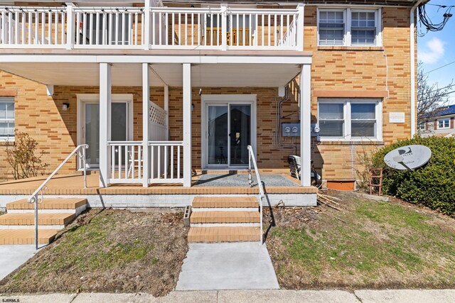 view of exterior entry featuring brick siding and covered porch