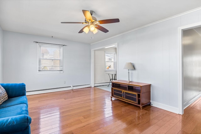 living area with ornamental molding, wood-type flooring, baseboard heating, and ceiling fan