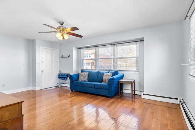 living area featuring hardwood / wood-style flooring, a ceiling fan, and a baseboard radiator