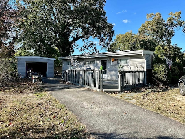 view of front facade featuring aphalt driveway, a detached garage, a wooden deck, and an outdoor structure