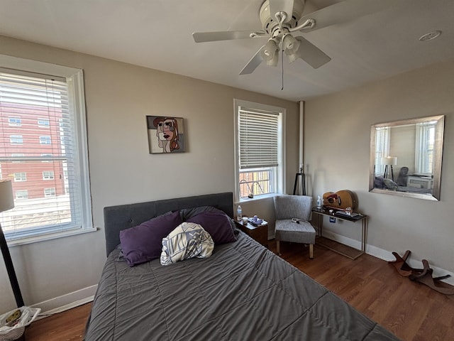 bedroom with multiple windows, a ceiling fan, baseboards, and wood finished floors