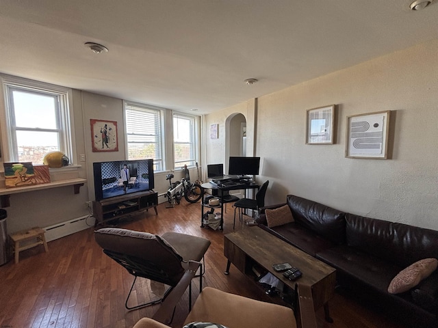 living area featuring arched walkways, baseboard heating, and wood-type flooring