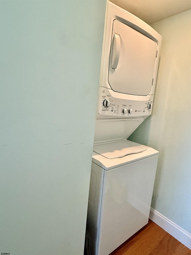 336 Bay Ave Unit 605, Ocean City, NJ 08226 - laundry room featuring stacked washer and dryer, baseboards, laundry area, and wood finished floors