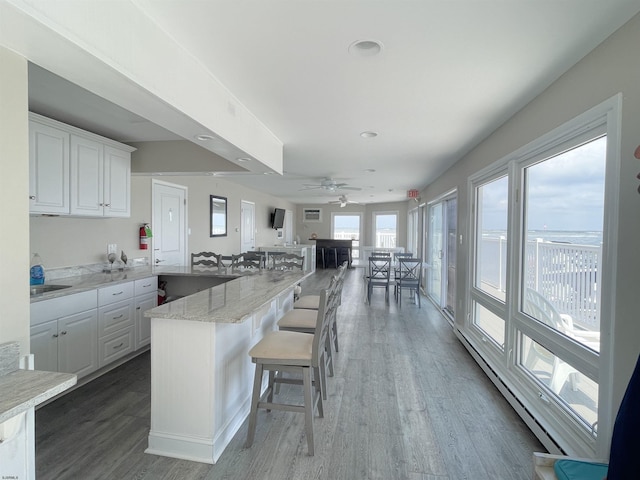 336 Bay Ave Unit 605, Ocean City, NJ 08226 - kitchen featuring white cabinetry, a baseboard radiator, a breakfast bar area, and wood finished floors
