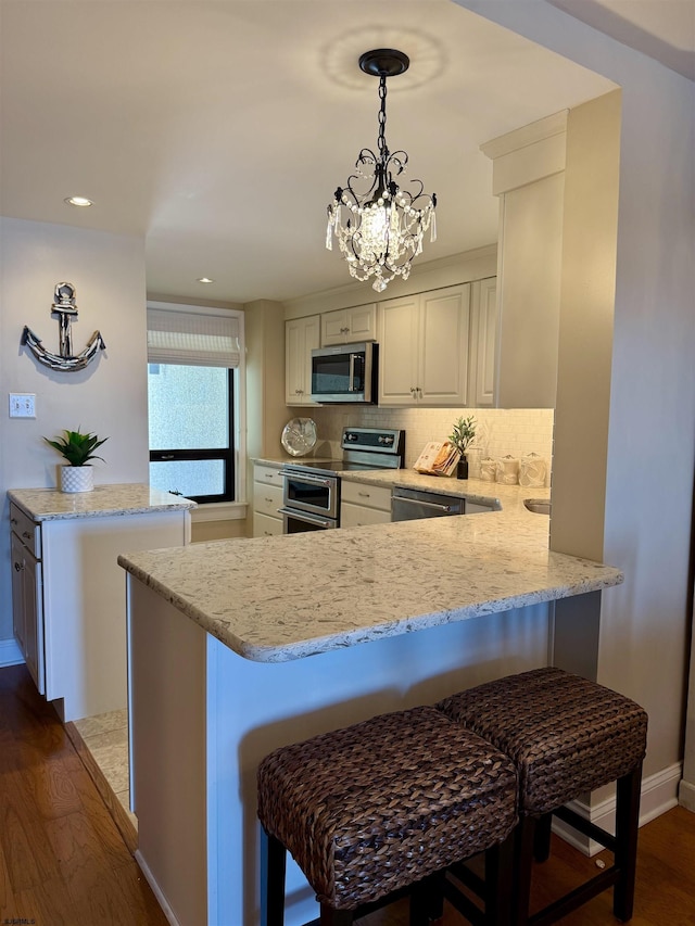 336 Bay Ave Unit 605, Ocean City, NJ 08226 - kitchen featuring dark wood-style flooring, a peninsula, appliances with stainless steel finishes, and light stone countertops
