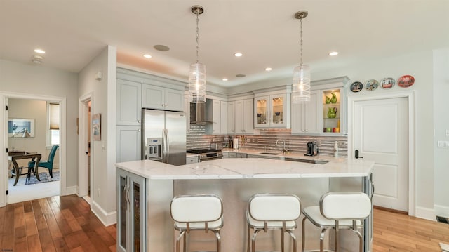 1905 Glenwood Dr, Ocean City, NJ 08226 - kitchen featuring light stone countertops, hardwood / wood-style flooring, appliances with stainless steel finishes, backsplash, and a kitchen breakfast bar