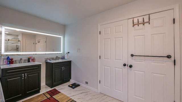 bathroom featuring marble finish floor, baseboards, a sink, and two vanities