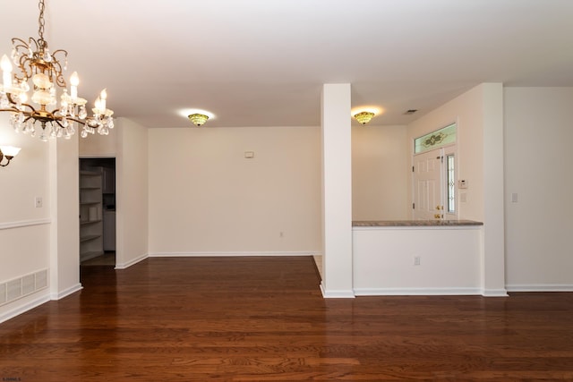 unfurnished room featuring a chandelier, wood finished floors, baseboards, and visible vents