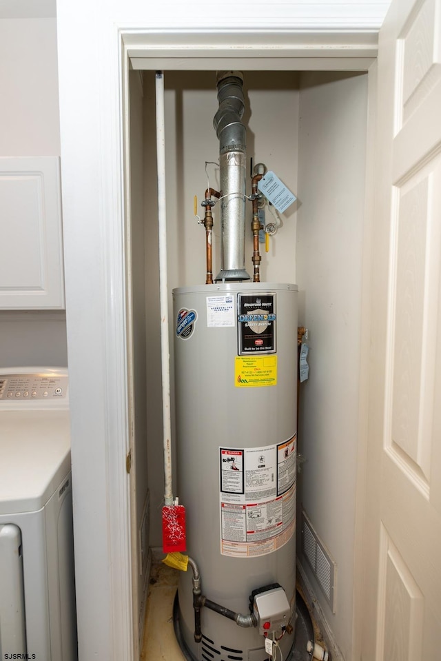 utilities featuring water heater, visible vents, and washer / dryer