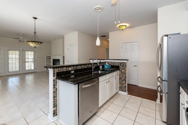 kitchen with open floor plan, a ceiling fan, light tile patterned flooring, stainless steel appliances, and a sink