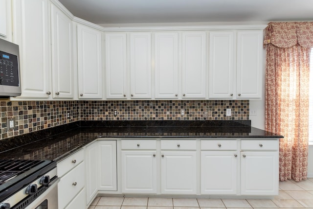 kitchen with light tile patterned flooring, white cabinets, dark stone counters, decorative backsplash, and stainless steel appliances