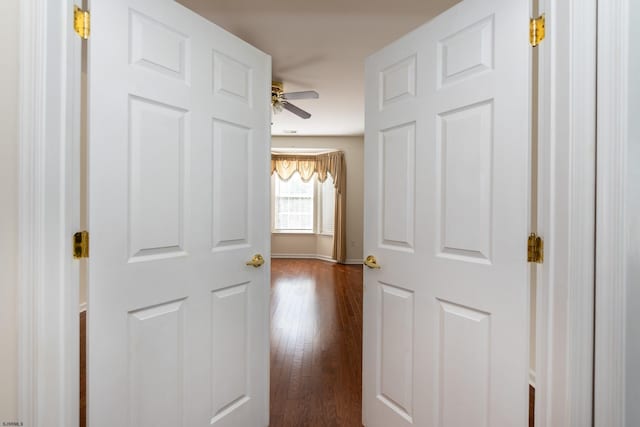corridor featuring baseboards and dark wood finished floors