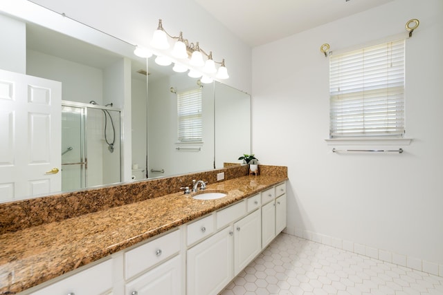full bathroom featuring vanity, baseboards, a stall shower, and a healthy amount of sunlight