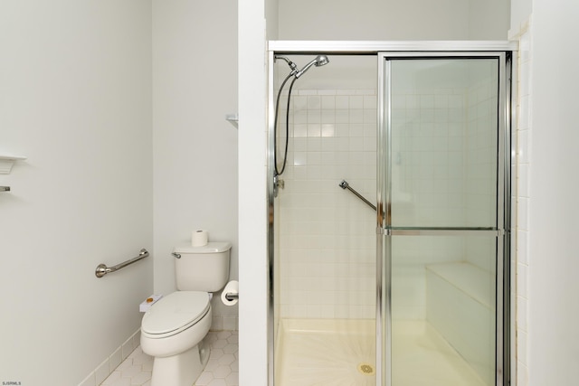 full bath with toilet, a stall shower, baseboards, and tile patterned flooring