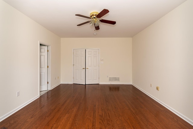 interior space with ceiling fan, baseboards, visible vents, and dark wood-style flooring
