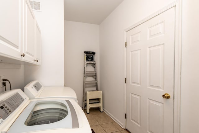 clothes washing area with baseboards, light tile patterned floors, visible vents, washer and clothes dryer, and cabinet space