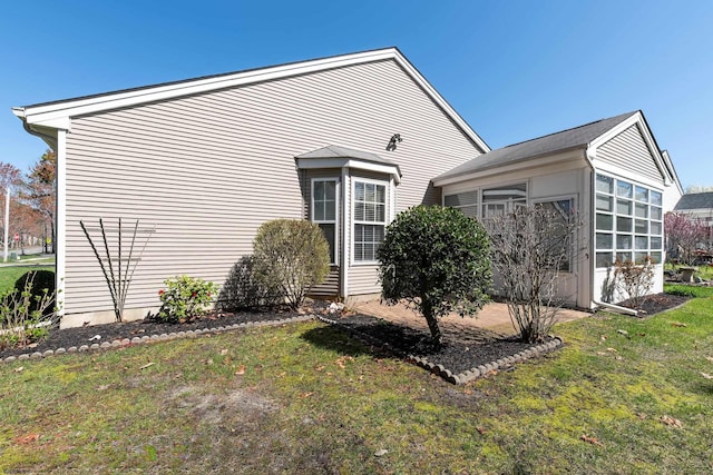 view of home's exterior featuring a sunroom and a lawn