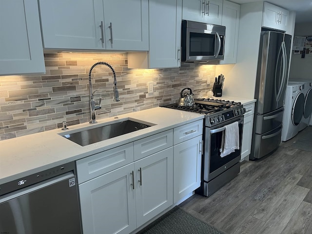 24 Greate Bay Dr Unit 24, Somers Point, NJ 08244 - kitchen with appliances with stainless steel finishes, independent washer and dryer, a sink, dark wood-style flooring, and backsplash