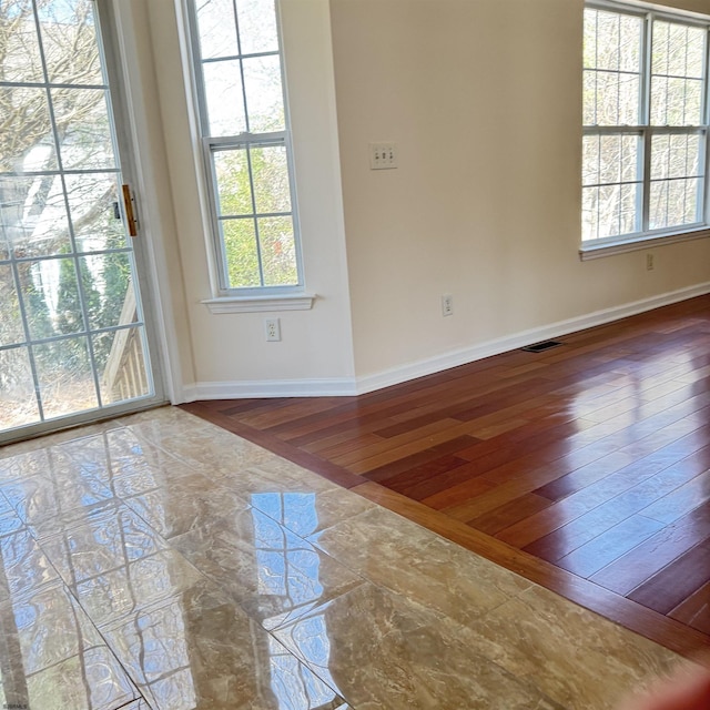 unfurnished room featuring visible vents, baseboards, and hardwood / wood-style flooring