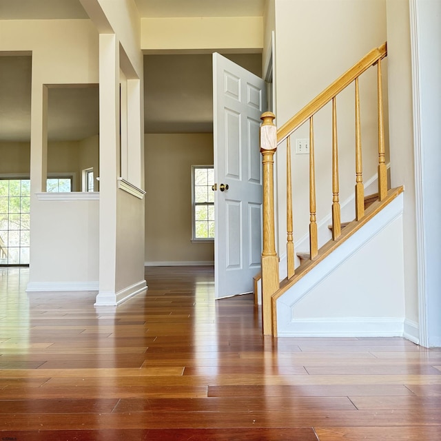 stairway featuring hardwood / wood-style floors, a healthy amount of sunlight, and baseboards