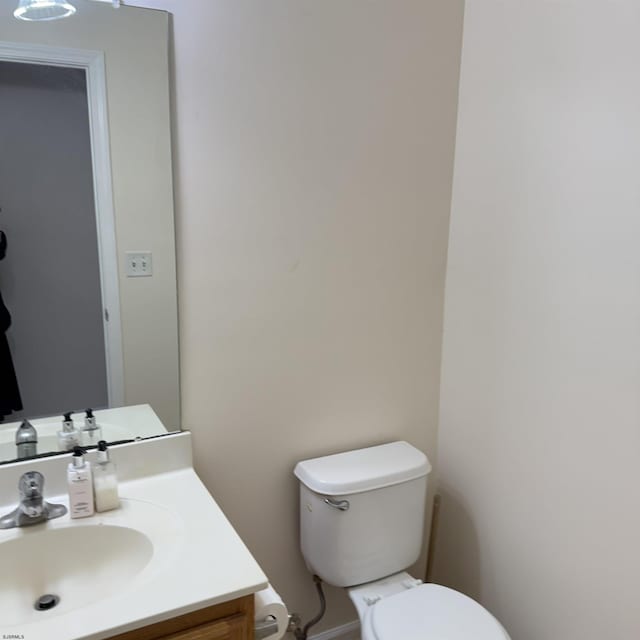 half bathroom featuring vanity, baseboards, and toilet