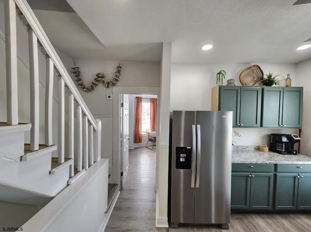 kitchen featuring stainless steel fridge with ice dispenser, light wood-style flooring, recessed lighting, and a textured ceiling