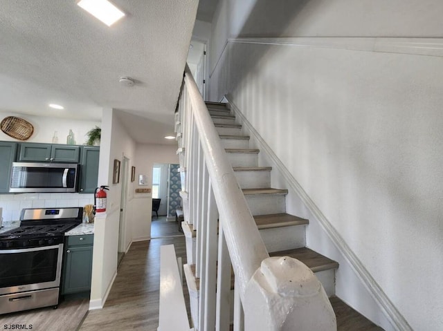 staircase with wood finished floors and a textured ceiling