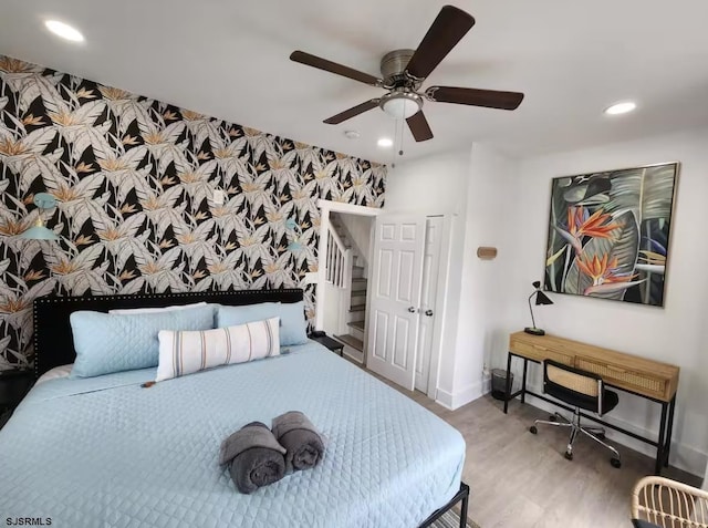 bedroom featuring an accent wall, recessed lighting, wood finished floors, wallpapered walls, and baseboards