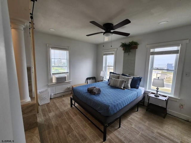 bedroom featuring baseboards, ceiling fan, a baseboard heating unit, and wood finished floors
