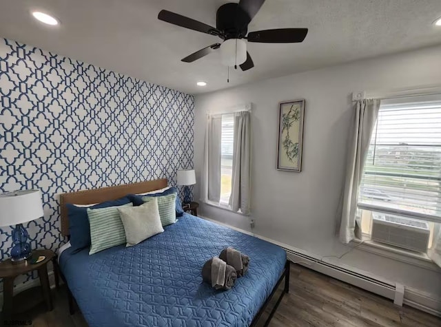 bedroom with a baseboard heating unit, wallpapered walls, recessed lighting, an accent wall, and wood finished floors