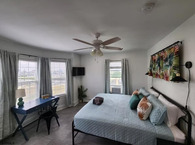 bedroom featuring a baseboard heating unit, baseboards, multiple windows, and a ceiling fan