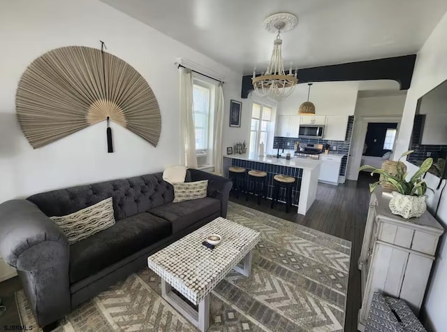 living room with dark wood-type flooring and a notable chandelier
