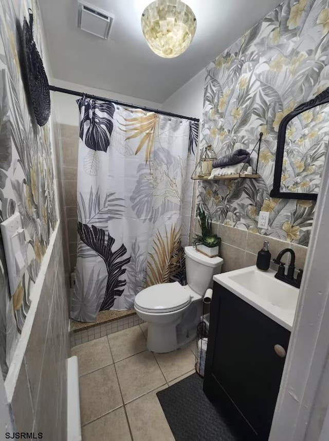 bathroom featuring vanity, tile patterned flooring, visible vents, toilet, and tile walls