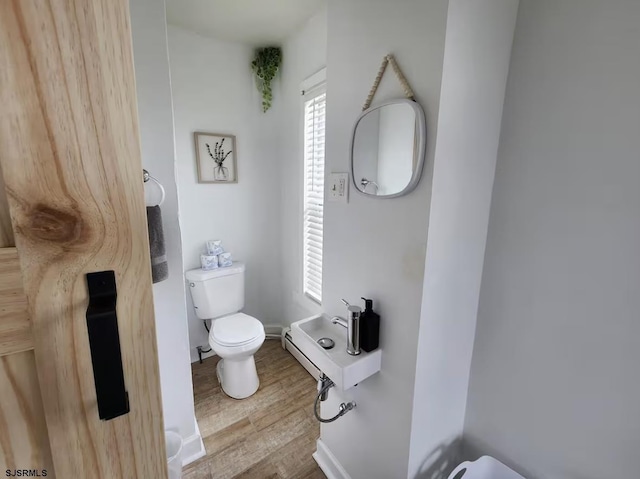 bathroom with baseboards, toilet, and wood finished floors