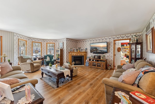 living room featuring wallpapered walls, light wood-style flooring, and a fireplace