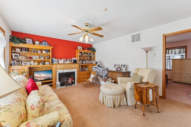 living room with a fireplace, visible vents, carpet flooring, and a ceiling fan