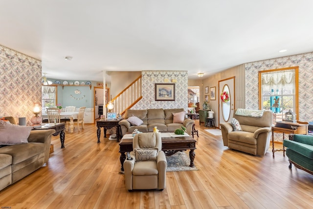 living area featuring stairs, wallpapered walls, and light wood-type flooring