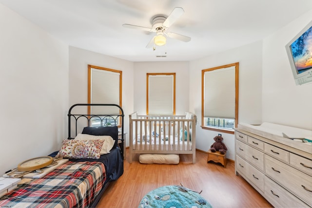 bedroom with visible vents, light wood finished floors, baseboards, and ceiling fan
