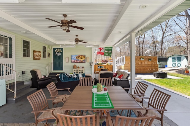 view of patio / terrace with an outbuilding, entry steps, outdoor dining space, and a shed