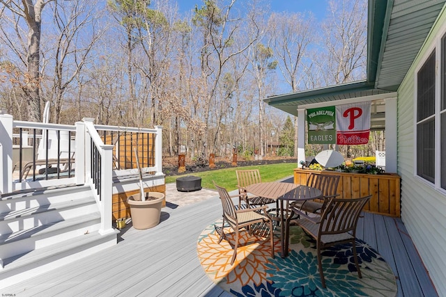 wooden deck featuring a lawn and outdoor dining area