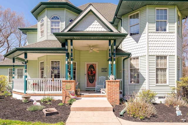 victorian house featuring ceiling fan, a shingled roof, and covered porch