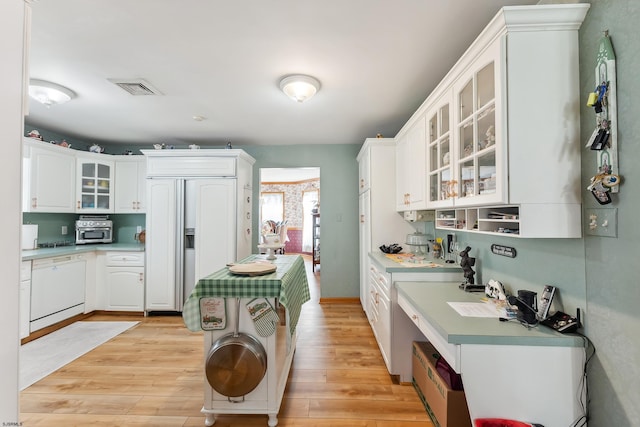 kitchen with light countertops, dishwasher, paneled built in refrigerator, light wood-style flooring, and white cabinetry