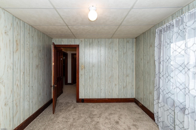 carpeted empty room with baseboards and a drop ceiling