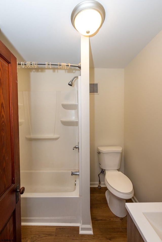 bathroom featuring baseboards, shower / washtub combination, toilet, vanity, and wood finished floors