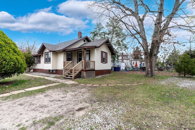 bungalow-style house featuring a porch, fence, a front lawn, a chimney, and a shingled roof