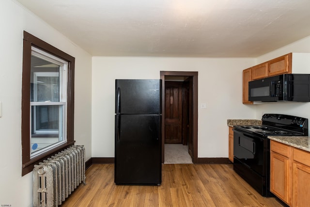 kitchen with light wood-style flooring, brown cabinetry, radiator heating unit, and black appliances