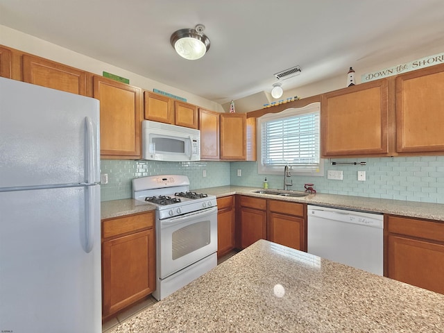 kitchen featuring white appliances, brown cabinetry, tasteful backsplash, visible vents, and a sink