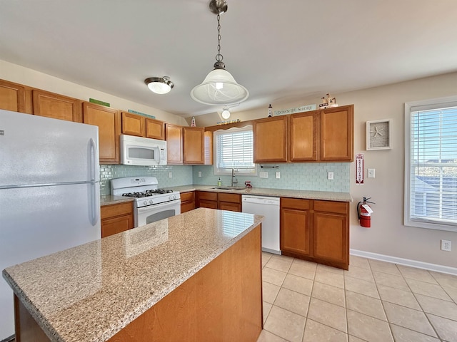 kitchen with light tile patterned floors, decorative backsplash, white appliances, and brown cabinetry